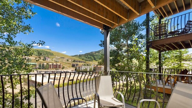 Un balcón con mobiliario exterior y vistas a un pueblo y colinas.