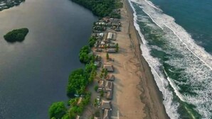 An aerial view of a coastal area with a river, beach, and small buildings along the shore. - Barra Zacapulco - Palapa Abrabam (Acapetahua)