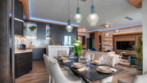 A modern kitchen with dark cabinets, a central island, and pendant lighting. - Villa Salute (Budva)
