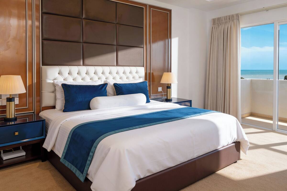 A hotel room with a large bed, a view of the ocean, and a balcony.