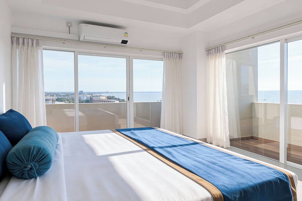 A hotel room with a large bed, a view of the sea, and a balcony.