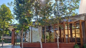 A modern outdoor seating area with wooden benches and a glass enclosure.