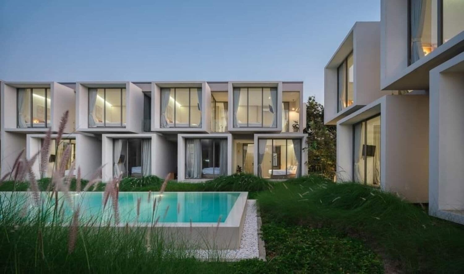 Un edificio moderno de varios pisos con una piscina en primer plano.