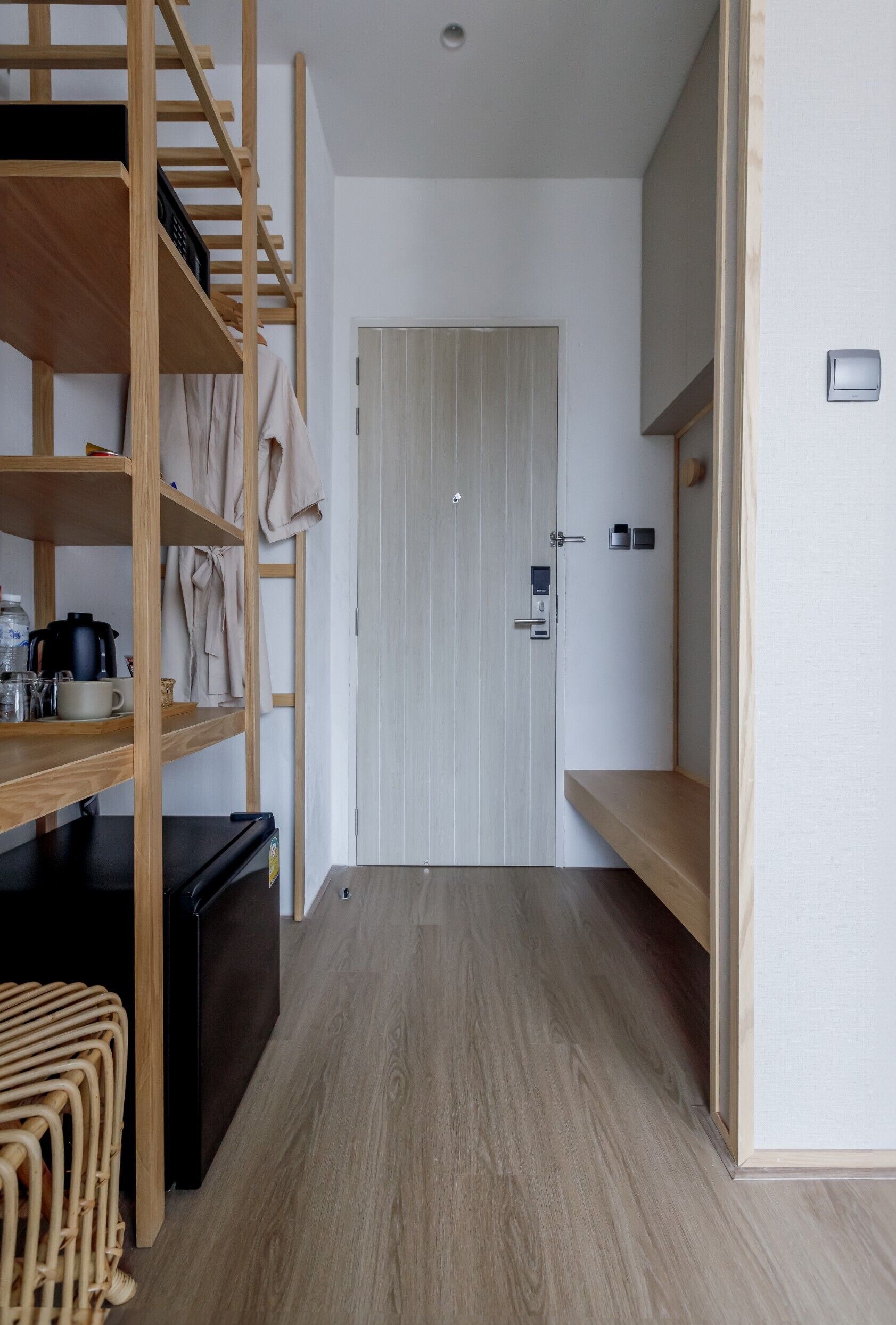 A compact room with a bunk bed, a small kitchenette, and a door leading to another room.