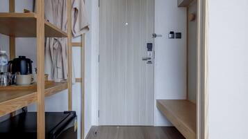 A compact room with a bunk bed, a small kitchenette, and a door leading to another room.