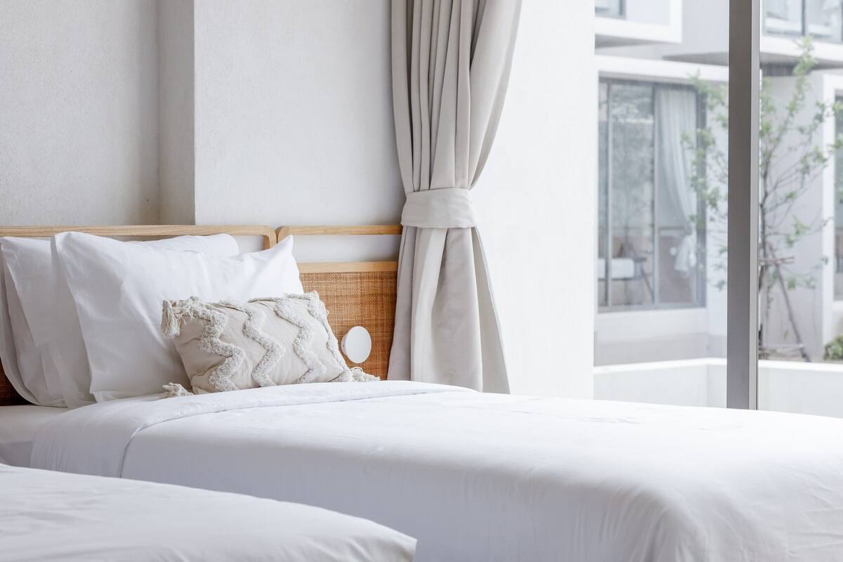 A neatly made bed with white bedding and a wooden headboard.