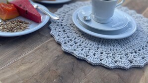 A table with a cup of coffee, a plate with watermelon and granola, and a plate with toast and jam, set outdoors with a pool in the background. - Pousada VIGLAMO JERI (Jijoca de Jericoacoara)