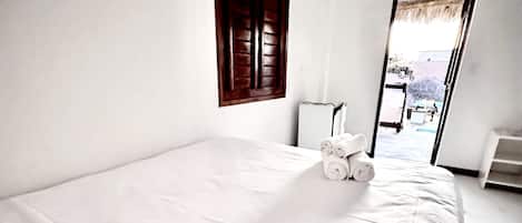 Una stanza pulita e luminosa con un letto grande, una finestra con persiane di legno e vista all'esterno.