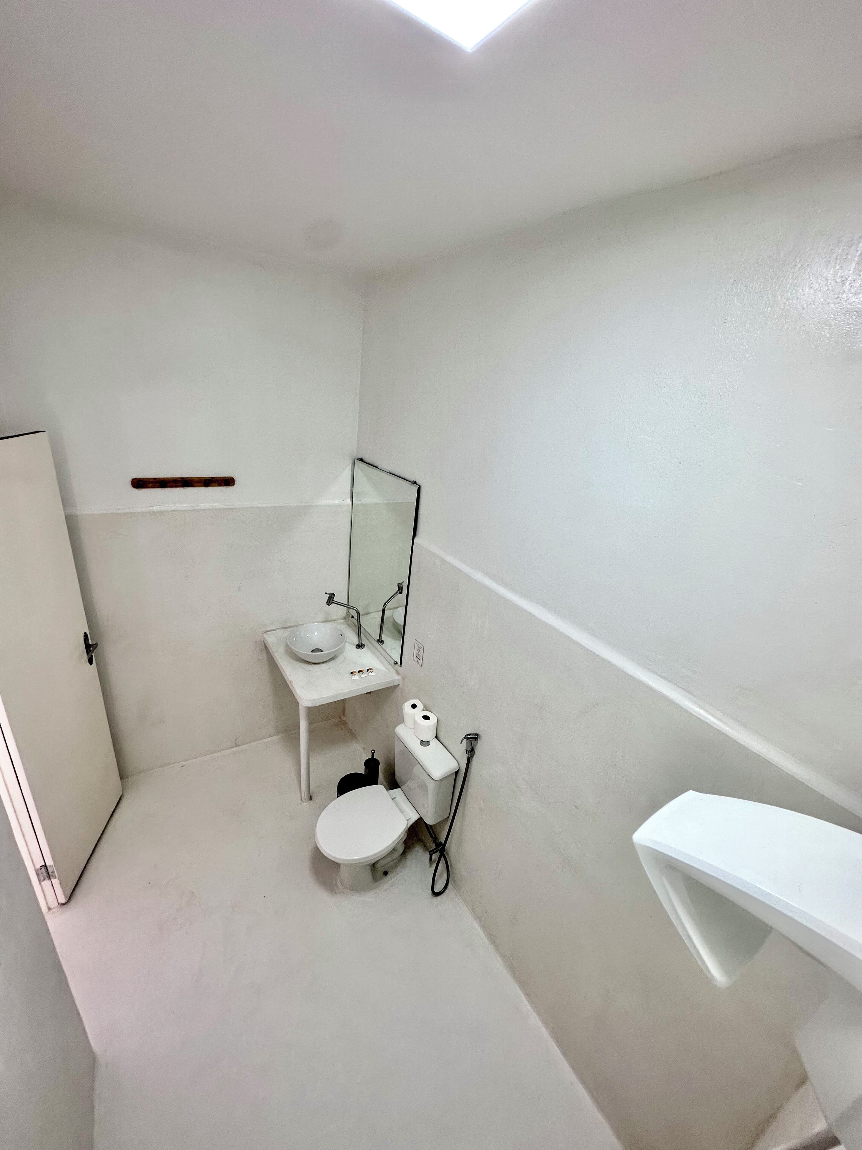 A small, white bathroom with a toilet, sink, and mirror.