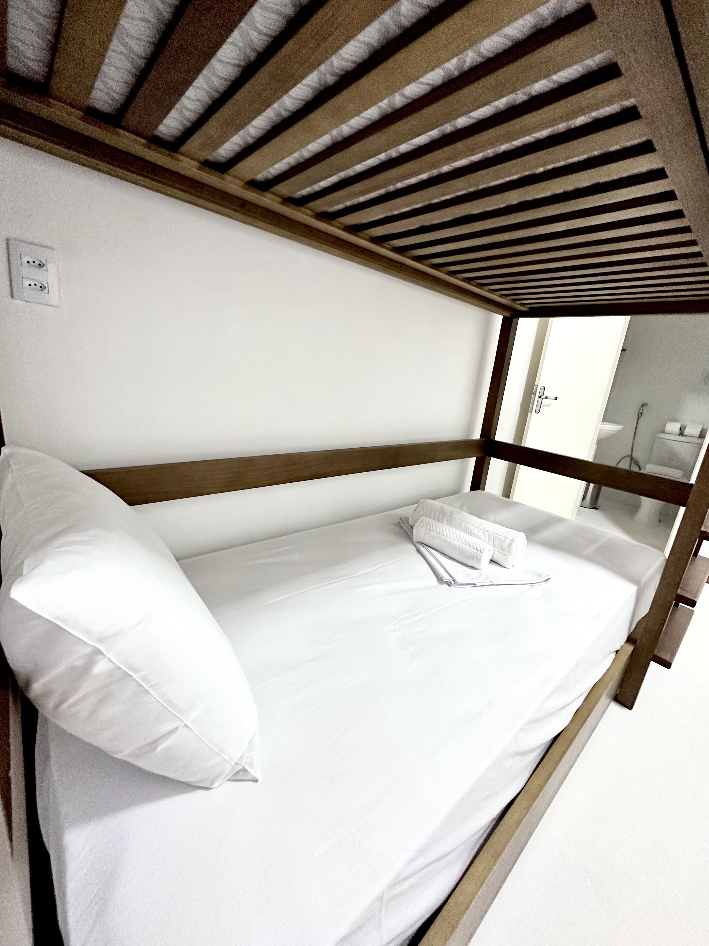 Una cama litera con ropa de cama blanca y un cabecero de madera.