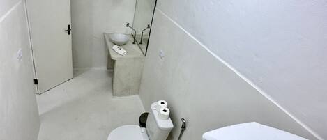 Un baño pequeño y blanco con inodoro, lavamanos y espejo.