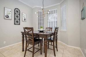 A dining area with a wooden table and chairs, a chandelier, and artwork on the walls.