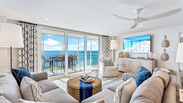 A spacious living area with a large sofa set, a television, and a view of the ocean through large sliding doors. - Beautiful Beach View Condo At Crystal Sands on Siesta Key! (Siesta Key)