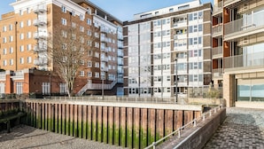 Kerrostalo, jossa on useita kerroksia, parvekkeita, puinen aita ja päällystetty kävelytie.