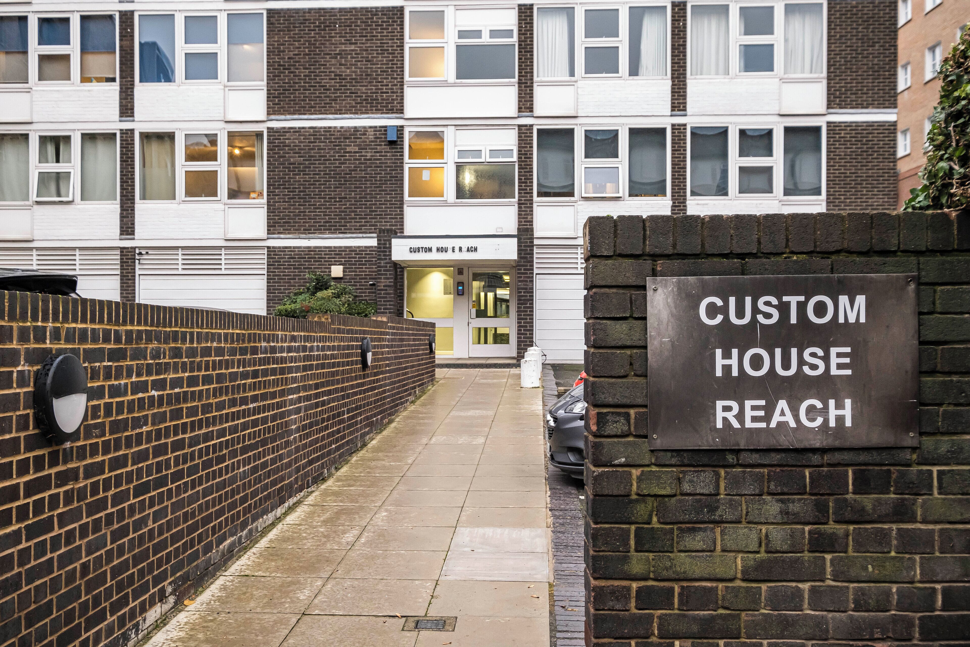 A brick wall with a sign reading "CUSTOM HOUSE REACH".