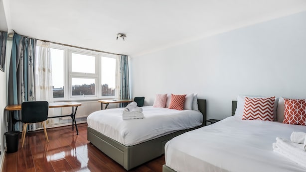 Hotellihuone, jossa on kaksi sänkyä, työpöytä ja näkymä kaupunkiin.