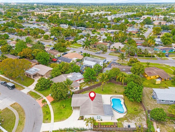 An aerial view of a residential area with houses, roads, and a swimming pool.