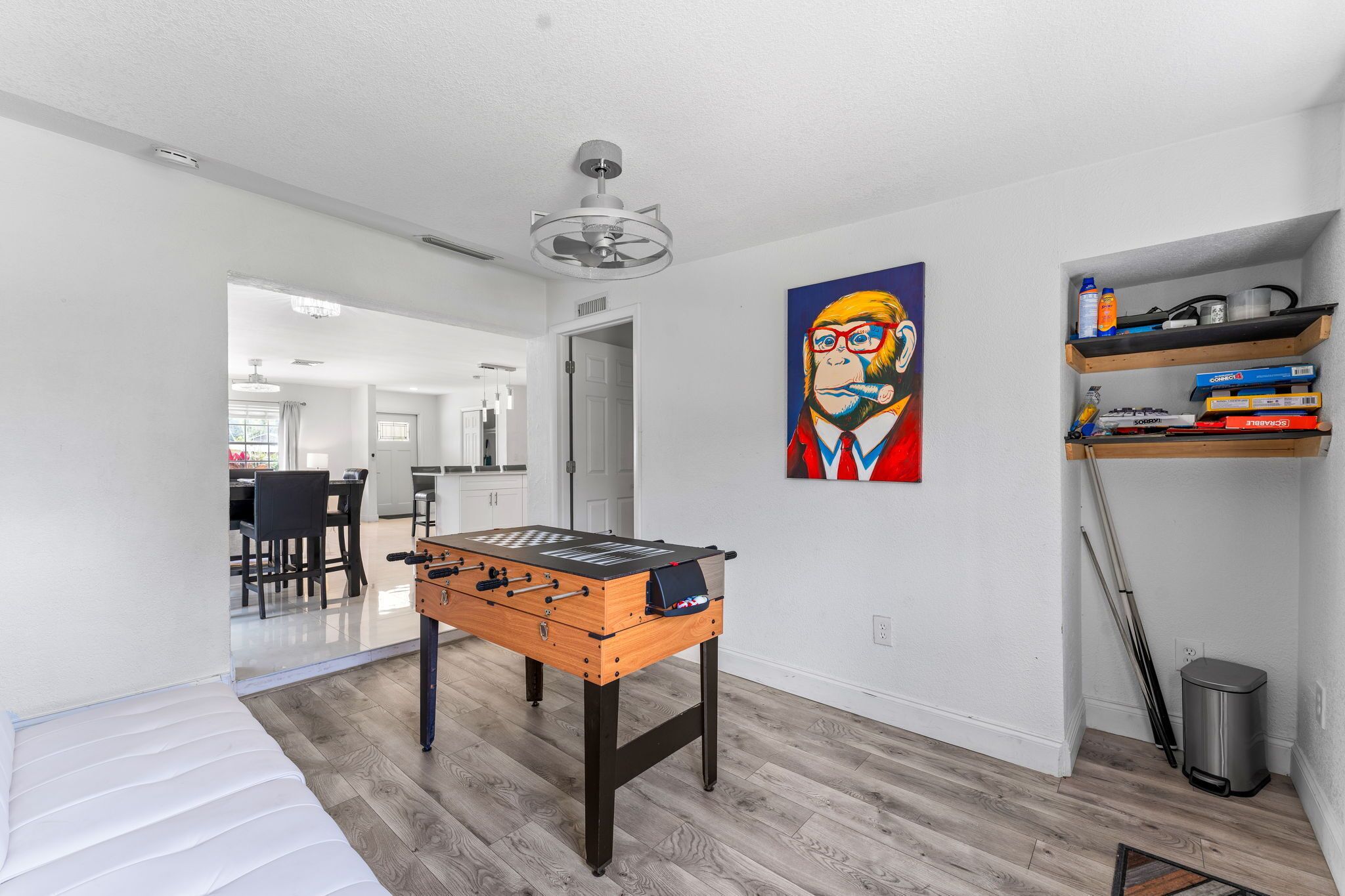 A modern living room with a foosball table, a painting, and a bookshelf.
