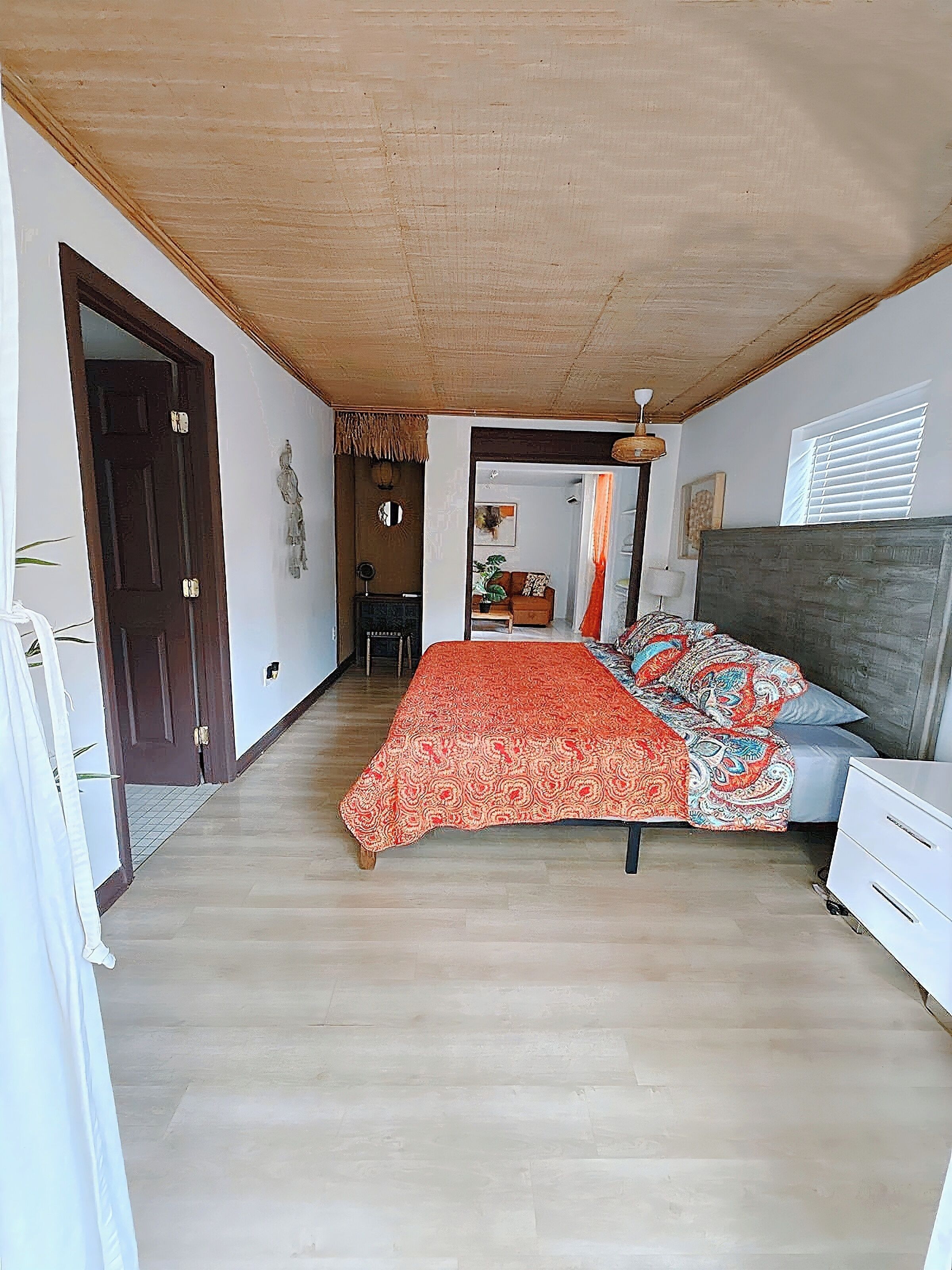 A bedroom with a bed, a nightstand, a dresser, and a window with blinds.