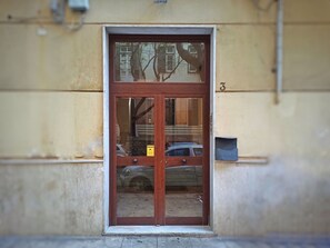 A wooden door with a glass panel, a yellow sign, and a mailbox on the wall.