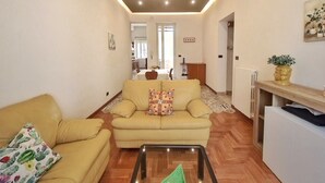 A living room with a sofa, a coffee table, and a dining area in the background. - Annacati House apartment, from 1 to 6 people, 3 bedrooms 2 bathrooms 1 terrace (Palermo)