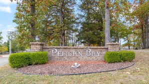 A brick wall with the words "PELICAN BAY" and two trimmed bushes. - Central Location, Unlimited Indoor & Outdoor Fun (Osage Beach)