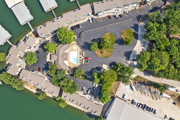 Een luchtendakfoto van een jachthaven met aangemeerde boten, een zwembad en een parkeerplaats.