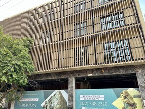 A modern building with a grid-like facade, large windows, and a tree in front. -  Maramara Centro (Sayulita)