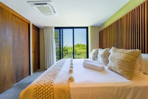 A modern bedroom with a large bed, wooden paneling, and a view of greenery outside. -  Maramara Centro (Sayulita)