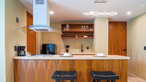 Une cuisine moderne dotée d’un îlot central, de meubles en bois et de deux tabourets de bar noirs.