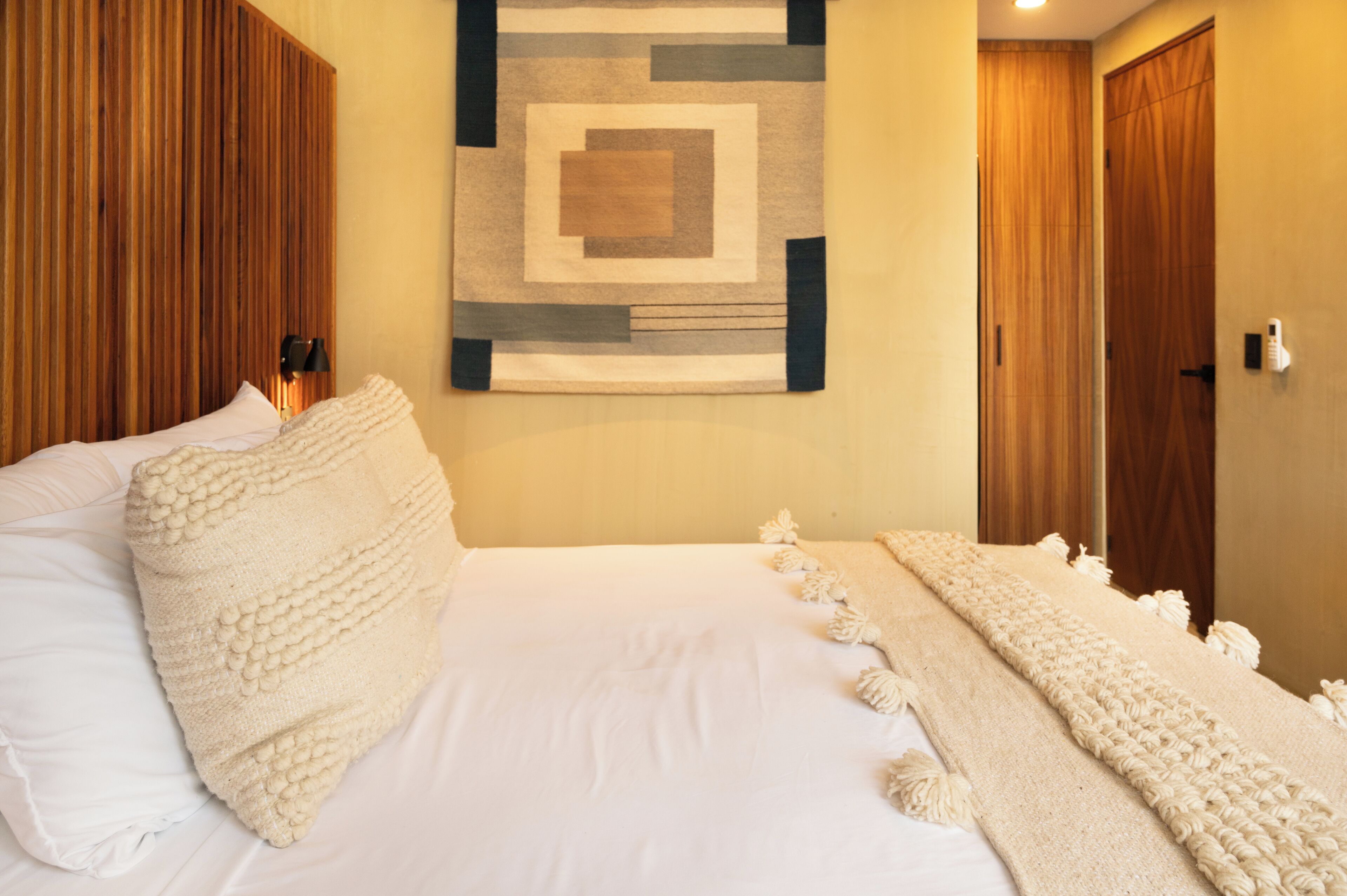 A neatly made bed with a white comforter and a decorative throw blanket.
