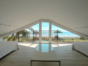 A bedroom with a large window overlooking a beach. - Front Row Newly Upgraded Bungalow #1 (Playa Hermosa)