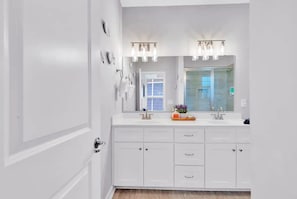 Une salle de bain moderne avec un meuble-lavabo à deux vasques, un grand miroir et une douche à parois de verre.