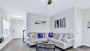 Una sala de estar moderna con un sofá seccional gris, una mesa de centro y un cuadro en la pared.