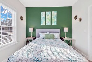 Camera da letto con un letto, due comodini, una parete verde e due opere d'arte appese al muro.