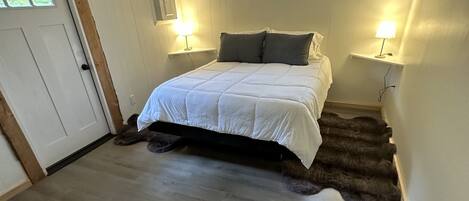 A bedroom with a bed, two bedside lamps, a window, and a door.