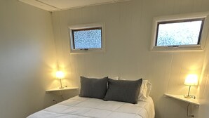 Quarto com uma cama grande, duas luminárias de cabeceira, uma janela e um tapete de pele.