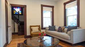 A living room with a round coffee table, a sofa, a chair, and a stained glass window.