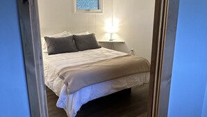 Een slaapkamer met een bed, een bedlampje en een raam.