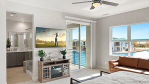 Une chambre moderne dotée d’un grand lit, d ’une télévision et d’un balcon avec vue sur la piscine.