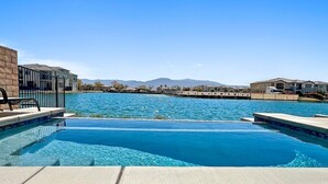 Une piscine à l’eau d’un bleu cristallin, entourée d’une terrasse en béton et d’un mur en briques.