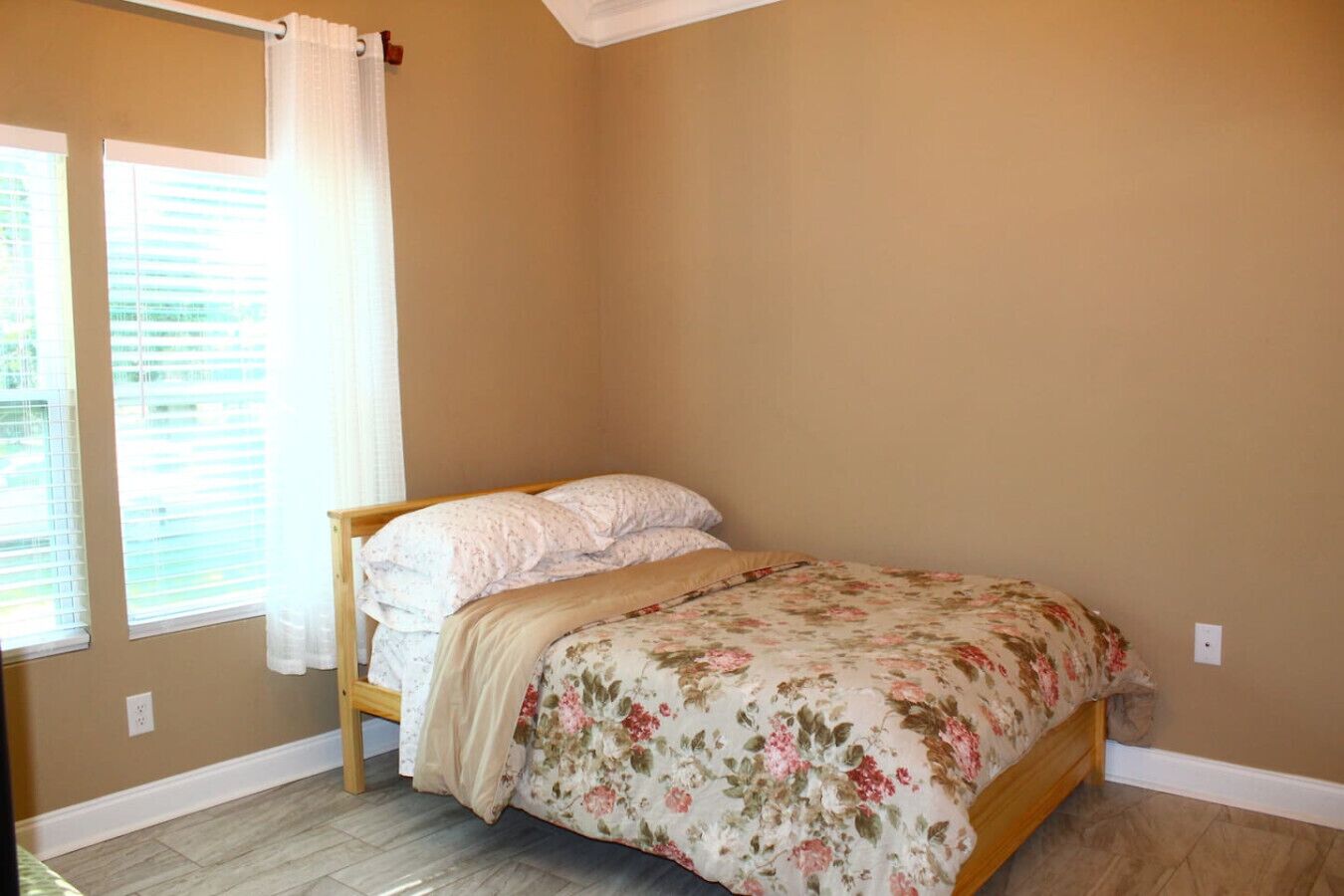 Quarto com uma cama, uma janela com persianas e uma porta.