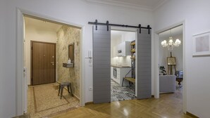 Un pasillo con suelo de madera, una puerta corredera gris y una cocina visible a través de ella.