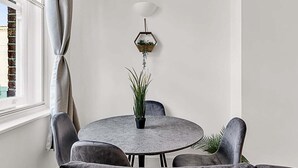 A round dining table with four chairs, a potted plant in the center, a hanging hexagonal planter with a plant, and a white ceiling light. - Contemporary Oasis in Paddington II (London)