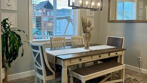 A dining area with a wooden table, chairs, a chandelier, and a view of a building through the window. - House in West Salem (Salem)