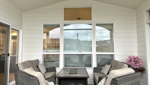 A covered patio with wicker furniture, large windows, and a small table. - House in West Salem (Salem)