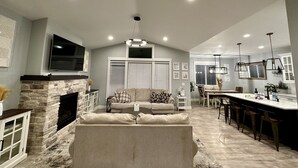A spacious living area with a stone fireplace, a large sofa, and a dining area with a long table and bar seating. - House in West Salem (Salem)