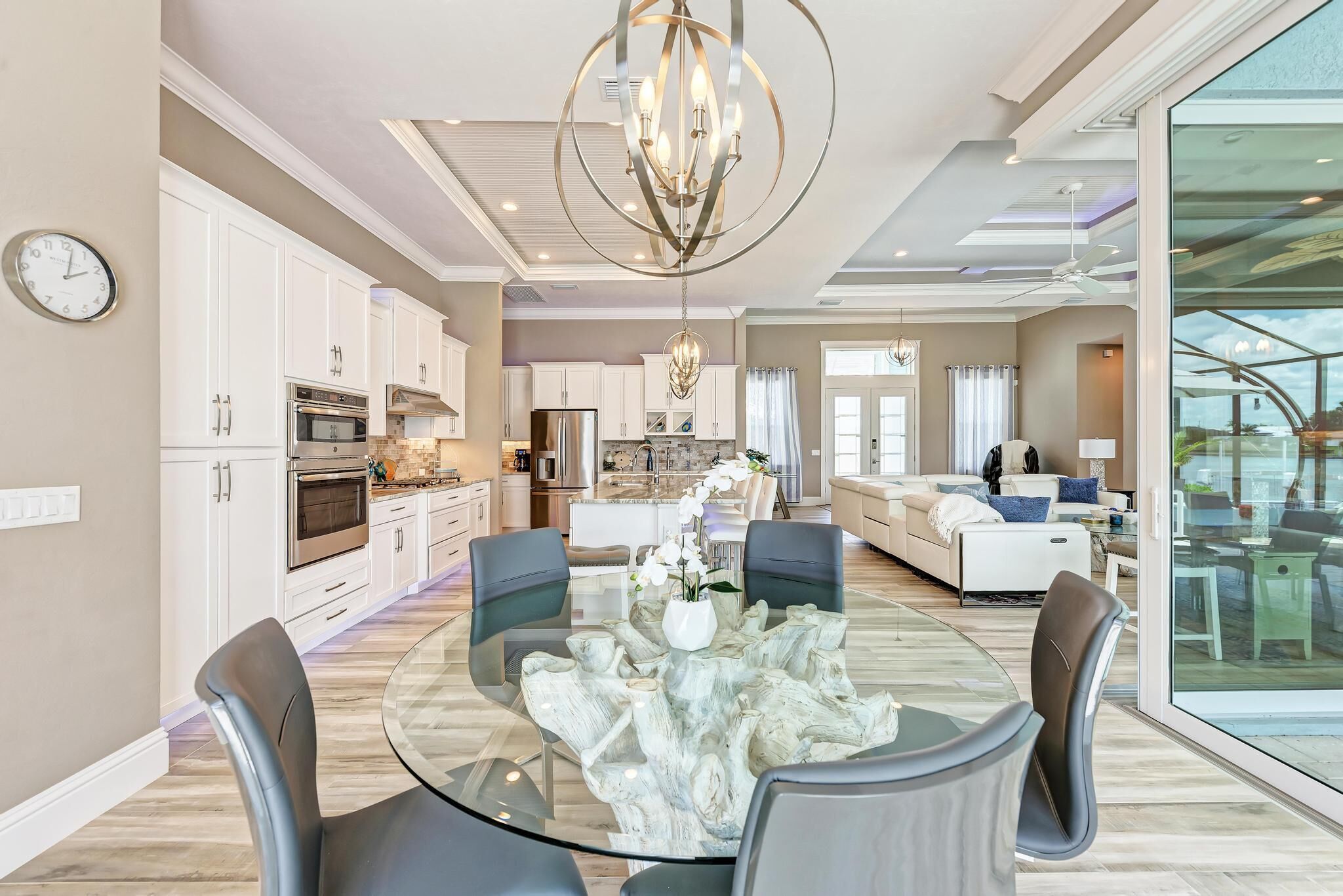 A modern kitchen with white cabinets, stainless steel appliances, and a dining area with a glass table and chairs.