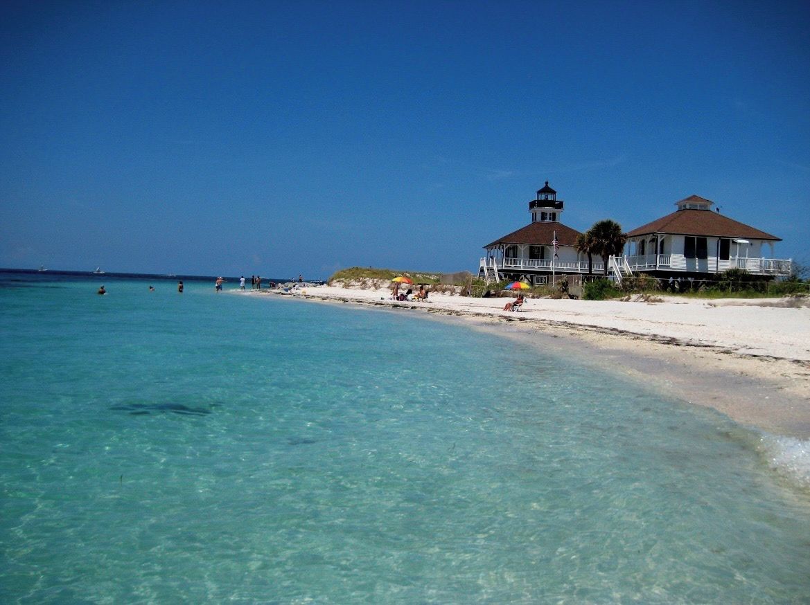 A beachfront property with a lighthouse, beach, and clear turquoise waters.