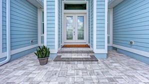 A house entrance with a double door, a small porch, and a potted plant. - Waterfront Luxury Retreat - Pool & Spa - Quick Harbor Access (Punta Gorda)